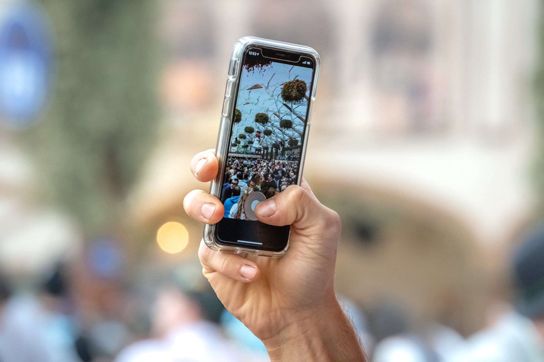 Eine Hand hält ein Smartphone und fotografiert den Zelthimmel