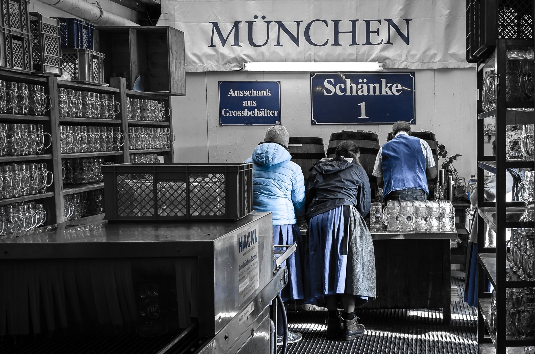 Schänke mit Regalen voller Maßkrüge, drei Frauen in blauen Schürzen von hinten